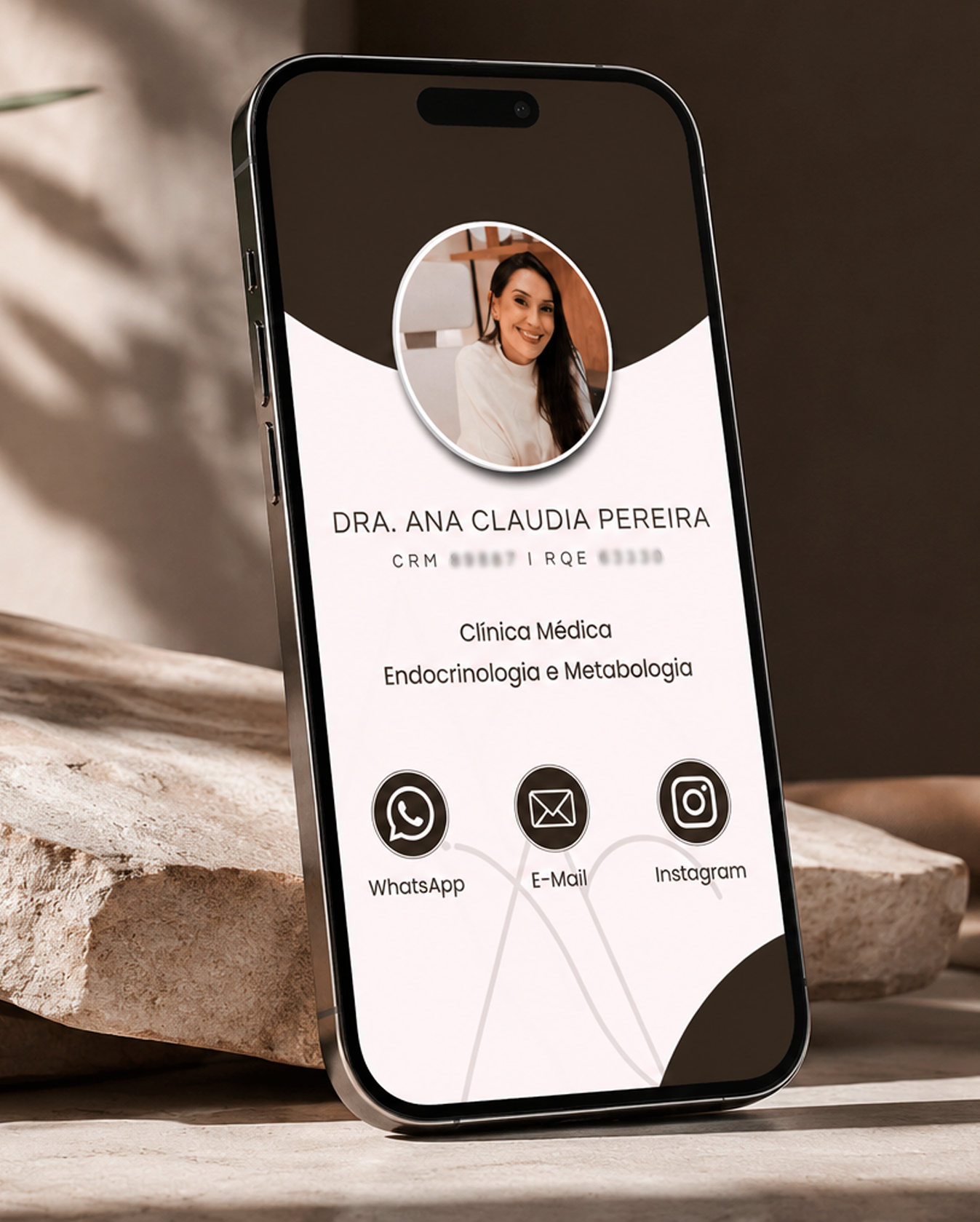 Mockup em um smartphone do cartão de visita digital e bio link desenvolvido pela Agencia azzy - marketing para medicos para Dra. Ana Claudia Pereira. A tela exibe a foto de perfil da médica em uma moldura circular, seu nome, dados de CRM e RQE, especialidades de Clínica Médica, Endocrinologia e Metabologia, e botões interativos para WhatsApp, E-mail e Instagram. O aparelho está apoiado sobre uma superfície de pedra natural.